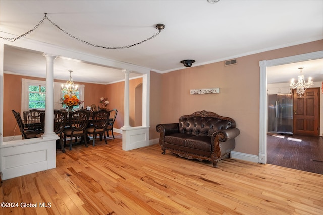 interior space with decorative columns, a chandelier, and light hardwood / wood-style floors