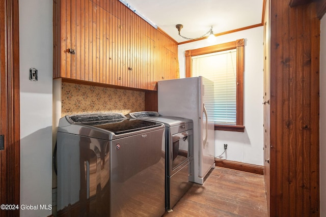 washroom with crown molding, cabinets, separate washer and dryer, and wood-type flooring