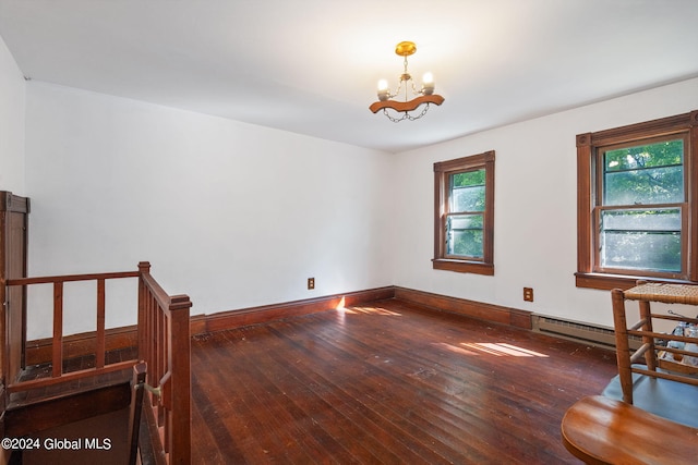 unfurnished room with a baseboard heating unit, a healthy amount of sunlight, dark hardwood / wood-style floors, and an inviting chandelier