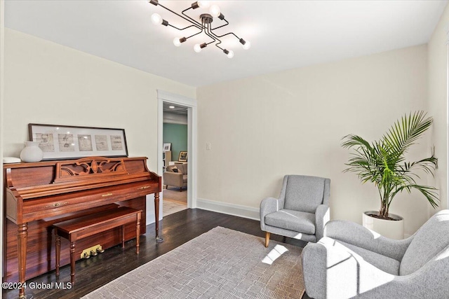 sitting room with dark wood-type flooring and an inviting chandelier