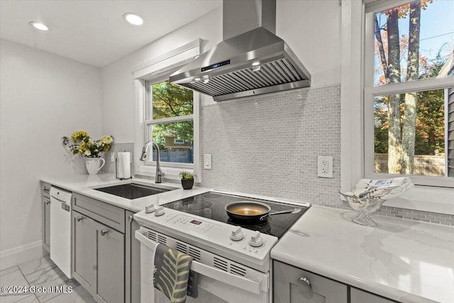 kitchen featuring gray cabinets, white appliances, light stone countertops, range hood, and sink