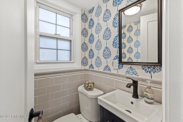 bathroom with toilet, vanity, and tile walls