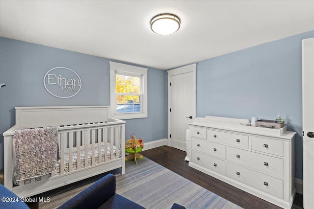 bedroom with dark wood-type flooring and a crib