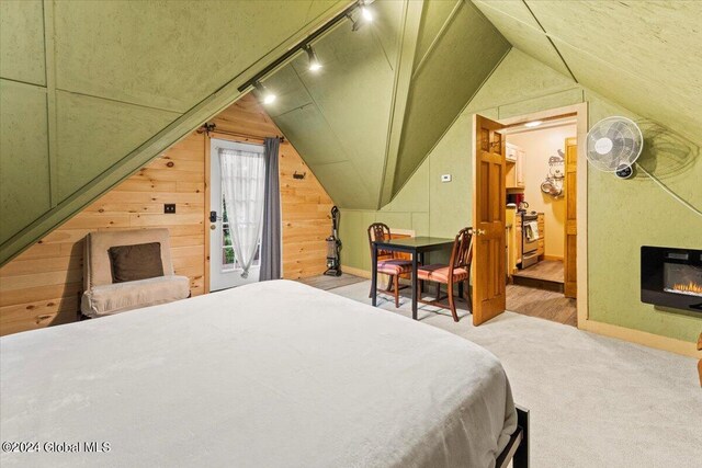 bedroom with wooden walls, track lighting, and lofted ceiling