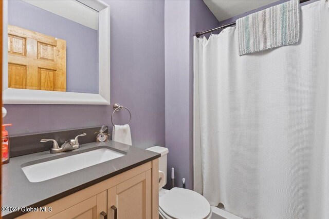 bathroom featuring curtained shower, vanity, and toilet