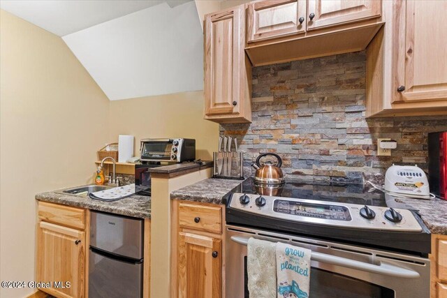 kitchen with stainless steel appliances, sink, light brown cabinetry, lofted ceiling, and decorative backsplash