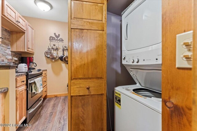 laundry area with stacked washing maching and dryer and hardwood / wood-style flooring