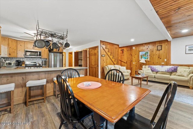 dining space featuring wood walls, light wood-type flooring, and ceiling fan