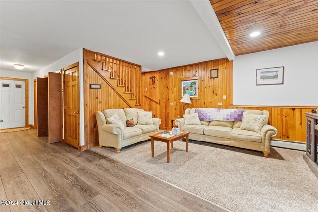 living room featuring wooden walls, hardwood / wood-style floors, and a baseboard heating unit