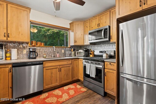 kitchen featuring dark hardwood / wood-style flooring, decorative backsplash, sink, ceiling fan, and appliances with stainless steel finishes