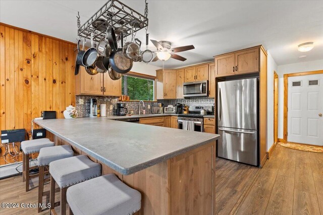 kitchen featuring kitchen peninsula, appliances with stainless steel finishes, dark wood-type flooring, and backsplash