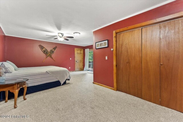 carpeted bedroom with ceiling fan and a closet