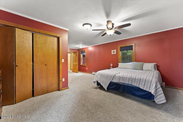 bedroom with light carpet, ornamental molding, ceiling fan, a baseboard radiator, and a closet