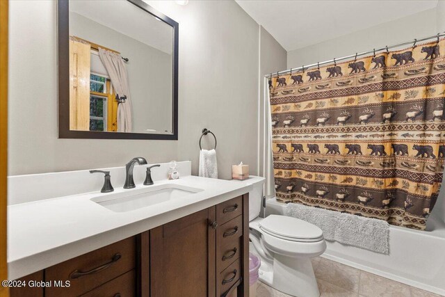 full bathroom with shower / bath combo with shower curtain, tile patterned floors, vanity, and toilet