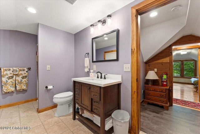 bathroom featuring vanity, hardwood / wood-style flooring, toilet, and vaulted ceiling