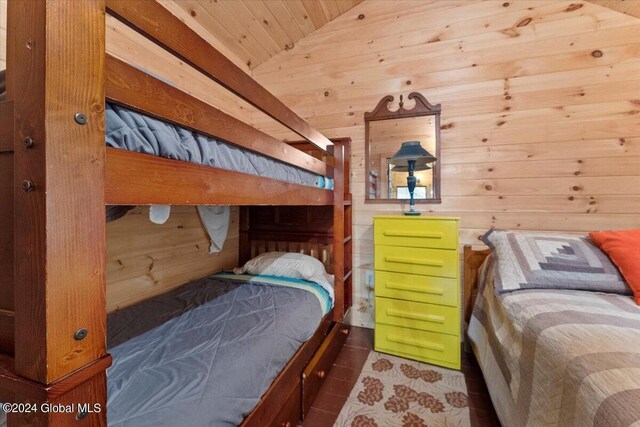 bedroom with tile patterned flooring, wooden walls, and lofted ceiling