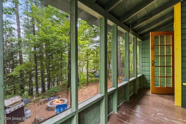 unfurnished sunroom with vaulted ceiling with beams