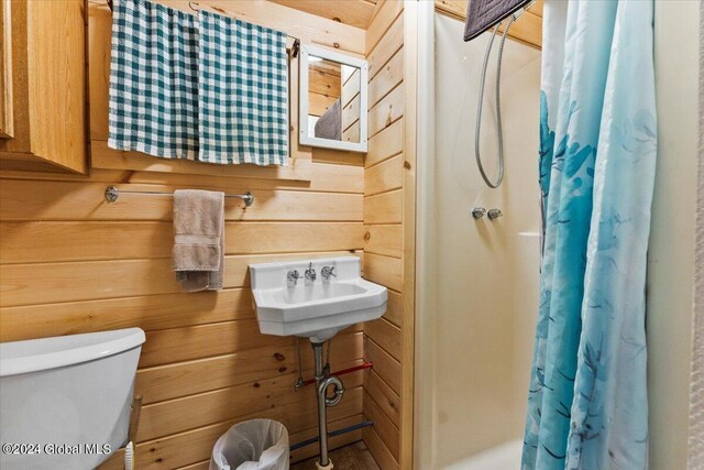 bathroom with toilet, wood walls, and curtained shower