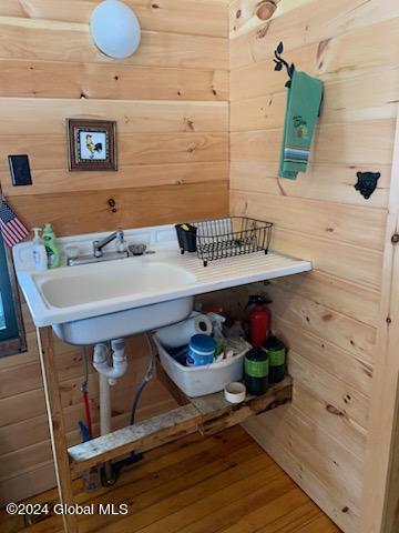 bathroom with wood walls, sink, and hardwood / wood-style floors