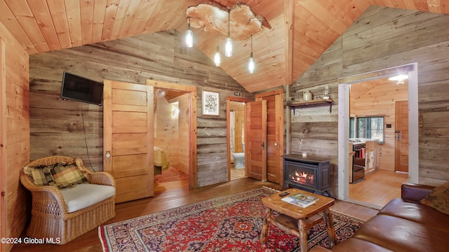 living room with a wood stove, hardwood / wood-style flooring, wooden walls, wooden ceiling, and high vaulted ceiling