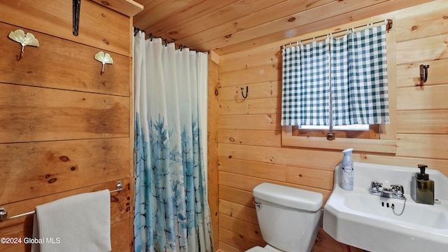 bathroom featuring wood walls, sink, toilet, and wooden ceiling