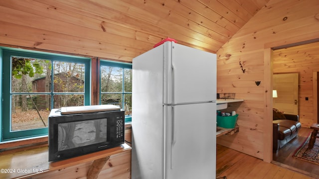 kitchen featuring lofted ceiling, wood ceiling, white refrigerator, wood walls, and light hardwood / wood-style flooring