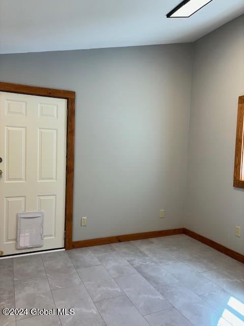 spare room with vaulted ceiling and light tile patterned flooring