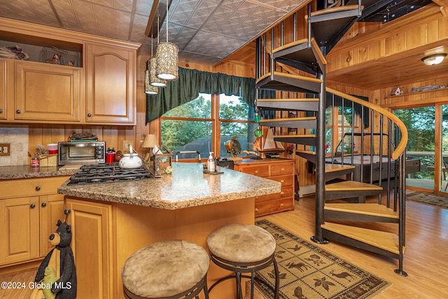 kitchen featuring wood walls, light hardwood / wood-style flooring, and light stone counters