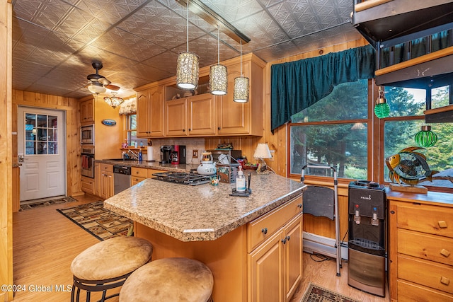 kitchen featuring a kitchen island, light wood-type flooring, ceiling fan, a breakfast bar area, and appliances with stainless steel finishes