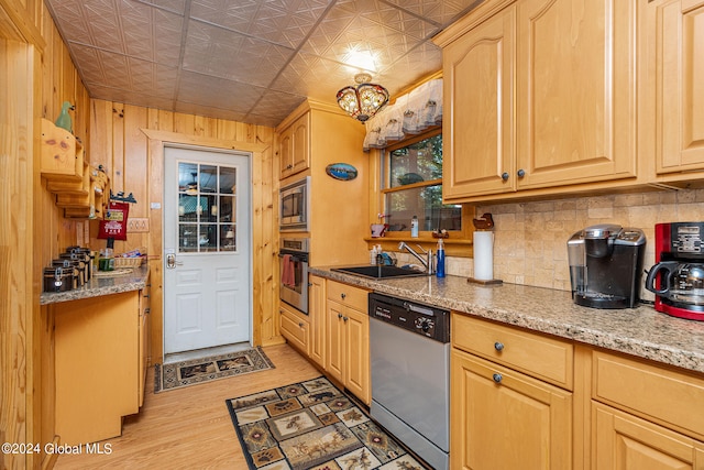 kitchen featuring wood walls, sink, wood-type flooring, stainless steel appliances, and light brown cabinetry