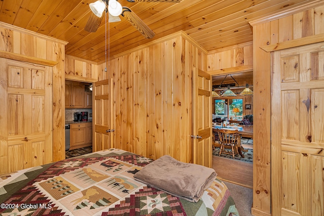 carpeted bedroom featuring wood walls, wood ceiling, and ceiling fan