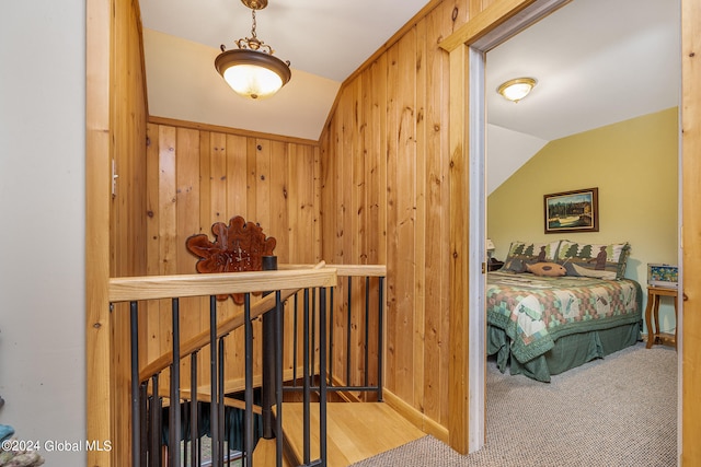 carpeted bedroom featuring lofted ceiling and wood walls