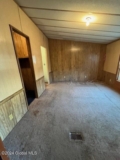 interior space with carpet and wooden walls