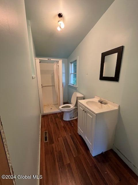 bathroom with a shower with shower curtain, vaulted ceiling, toilet, wood-type flooring, and vanity