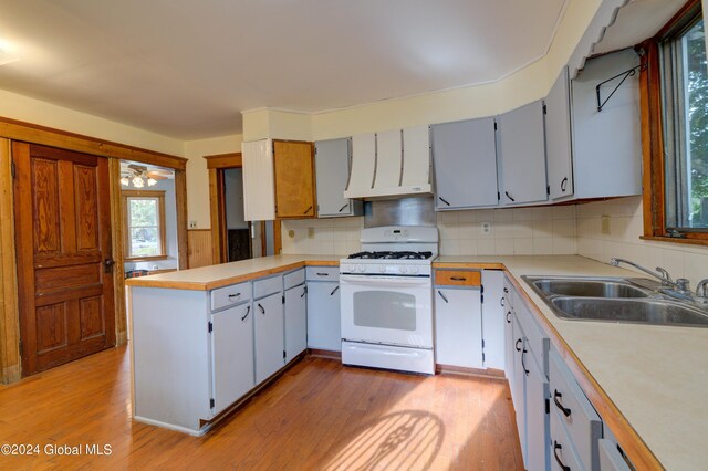 kitchen with light hardwood / wood-style flooring, white gas range, and sink