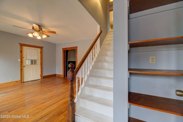 stairs featuring hardwood / wood-style flooring and ceiling fan