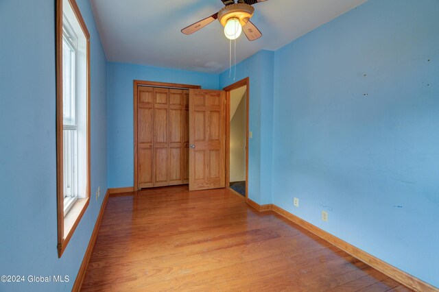 unfurnished bedroom with light wood-type flooring, ceiling fan, and a closet