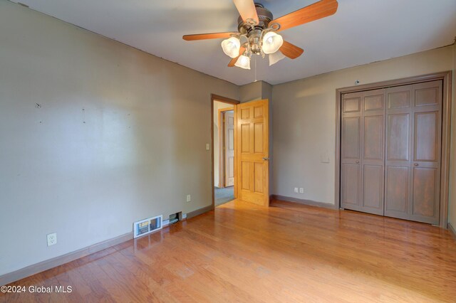 unfurnished bedroom featuring light hardwood / wood-style flooring, ceiling fan, and a closet