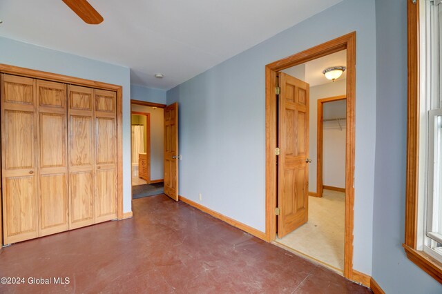 unfurnished bedroom featuring concrete floors, ceiling fan, and a closet