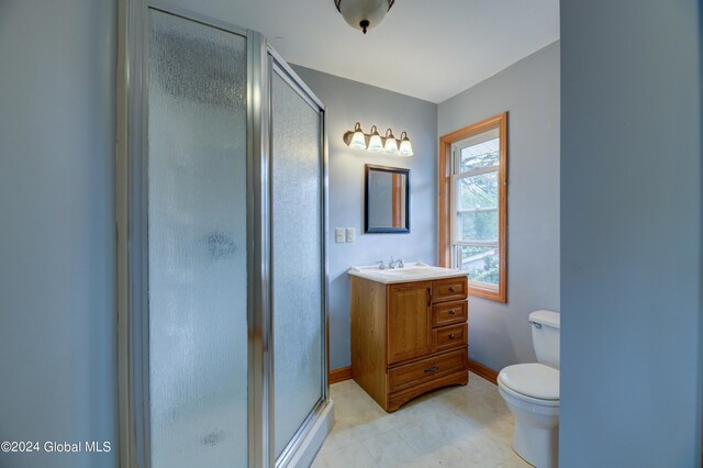 bathroom featuring vanity, toilet, tile patterned flooring, and a shower with door