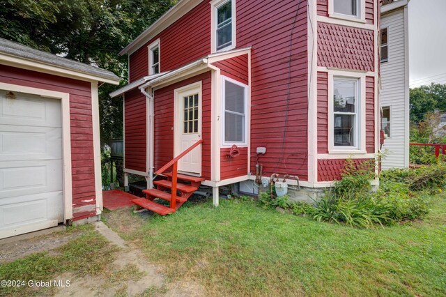 view of exterior entry with a lawn and a garage