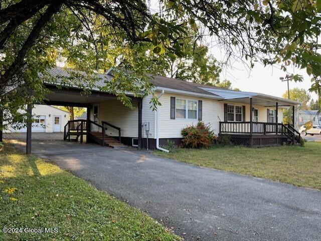 view of front of home with a porch, a front lawn, and a carport