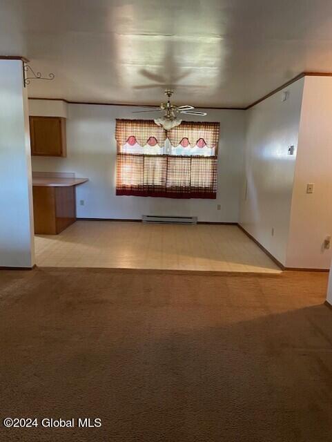 carpeted empty room with a baseboard heating unit and ceiling fan