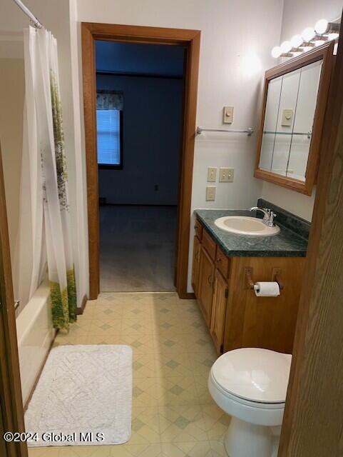 full bathroom featuring shower / bath combo with shower curtain, toilet, and vanity