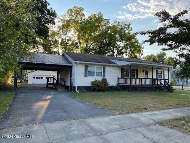 single story home with a porch, a carport, and a front lawn