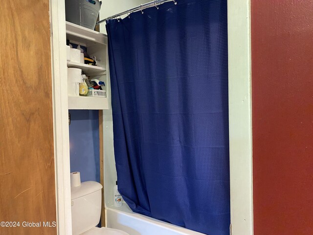 bathroom with shower / tub combo with curtain and toilet