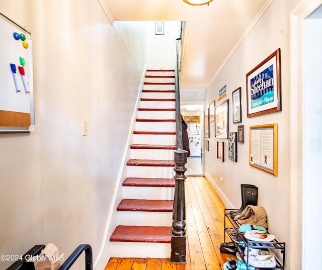 staircase featuring wood-type flooring and crown molding