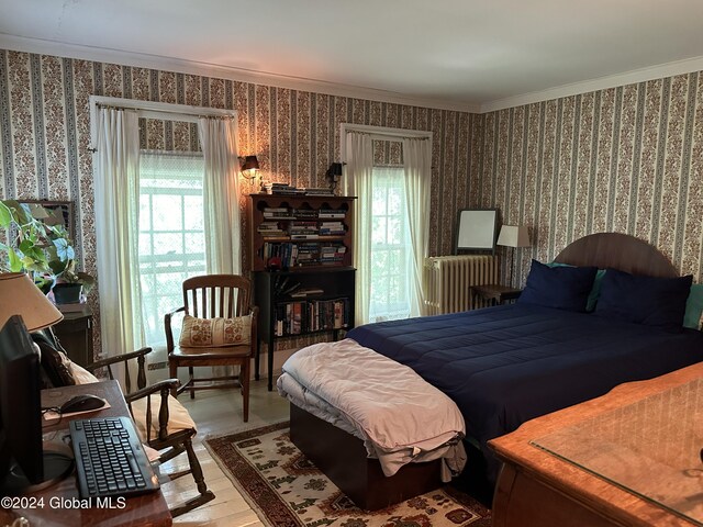 bedroom with crown molding, light hardwood / wood-style flooring, and radiator heating unit