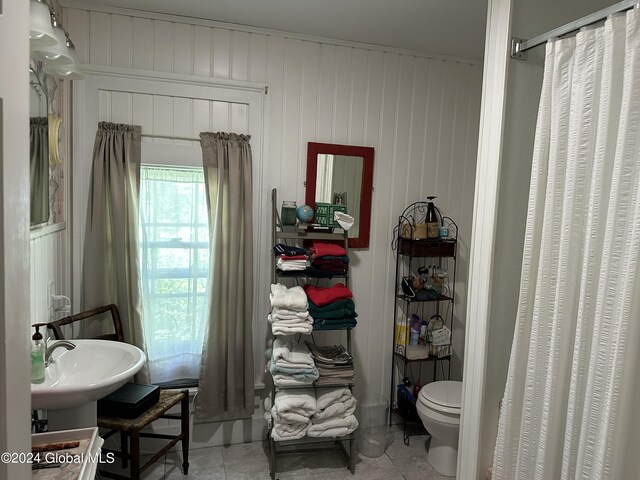 bathroom featuring toilet, wooden walls, tile patterned flooring, sink, and a shower with curtain