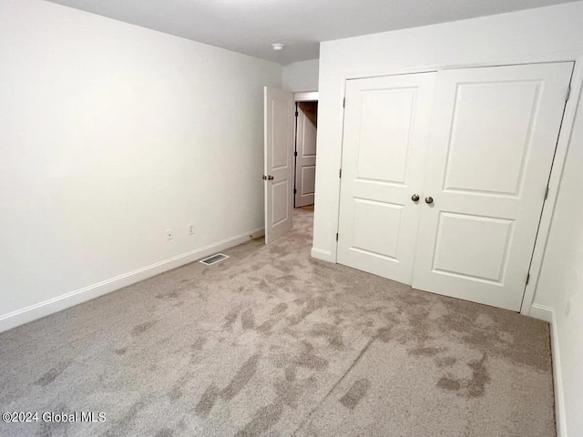 unfurnished bedroom with a closet and light colored carpet